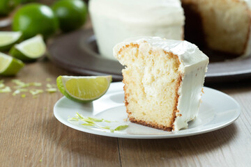 Close up piece of Moist lemon fruit cake on plate with lemon slices on wooden table. Delicious breakfast, traditional tea time. Lemon cake recipe.