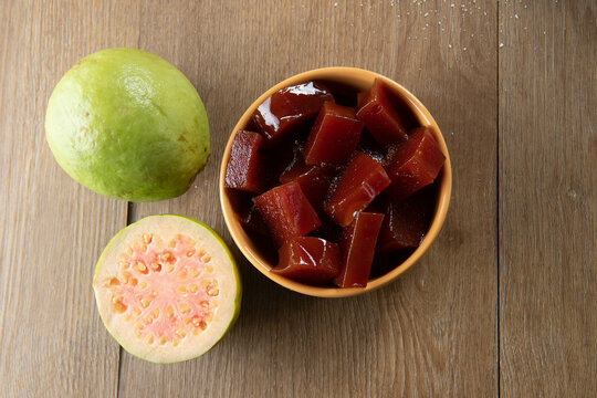 yellow can with guava jam cut into cubes with guavas in the background on wooden table