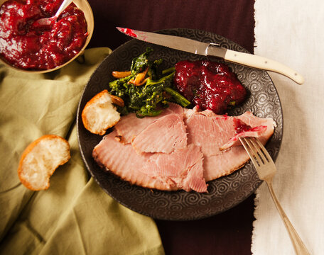 Plate with Slices of Baked Ham, Broccoli Rabe, Cranberry Sauce and Bread; From Above.