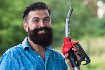 Portrait of a smiling man refueling car at the gas station. Man on petrol pump filling nozzles. Gas...
