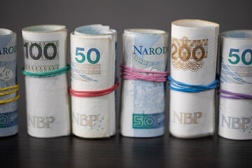 On the table there are Polish banknotes rolled up in a row and tied with a rubber band.