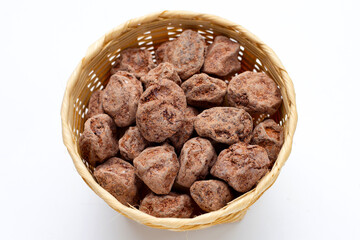 Dried salted Chinese plum in basket on white background