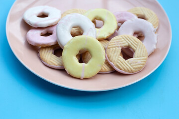 Cookie shapes donut in plate on blue background.