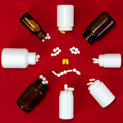 Fallen drug bottles arranged into circle around a goofy smiley made of medical pills and capsules on red background. Medication effects and pharmaceutical concept.