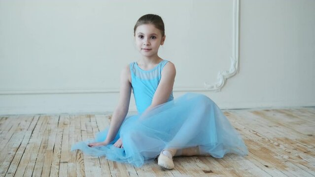 School of ballet. Little ballerina is sitting on the floor.