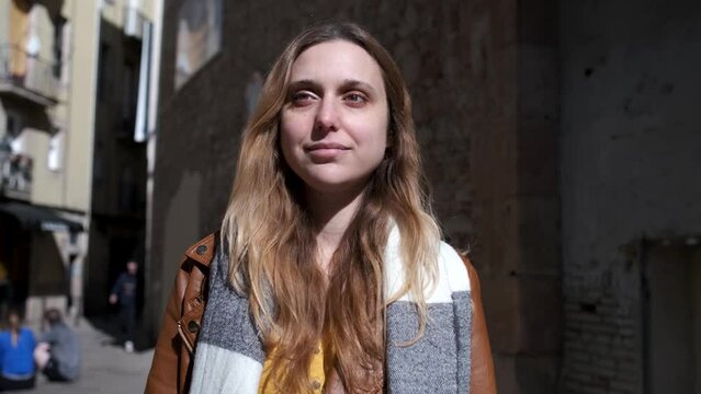 slow motion footage of an attractive trendy woman walking in street. She is weraring a brown leather jacket and scard