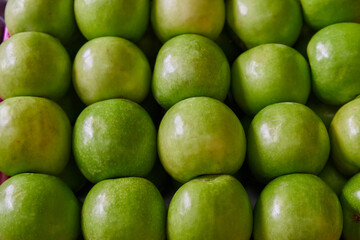 Green apples placed on a shelf for sale in a market