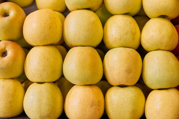 Yellow apples put on a shelf for sale within a market