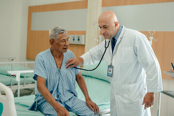 Hospitalized man sitting in bed while doctor checking his pulse. Doctor examining senior male...