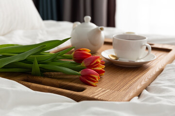 Breakfast in bed on a wooden table tray. light from the window. Flowers