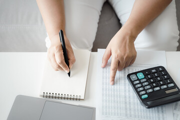 Woman is calculating annual tax with calculator and filling form of Individual Income Tax Return....