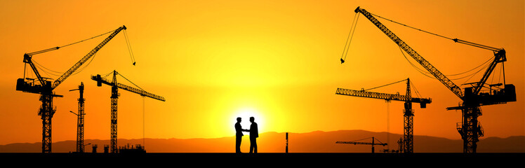 Crane concept in the construction industry. The silhouette of the crane in the construction site. handshake in construction business