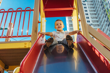 little boy slides down the slide at playground.