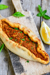  Traditional Turkish cuisine. Baked Pide dish with minced  beef, tomatoes and  herbs on  wooden background.  Turkish pizza pide