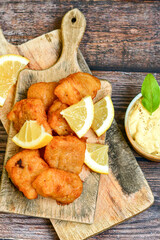   Allasca Pollock Fish  Bites in a crispy Tempura  Batter.Fish and chips .Close up of   crispy breaded  deep fried fish fingers with breadcrumbs s erved with remoulade sauce and  lemon