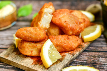   Allasca Pollock Fish  Bites in a crispy Tempura  Batter.Fish and chips .Close up of   crispy breaded  deep fried fish fingers with breadcrumbs s erved with remoulade sauce and  lemon