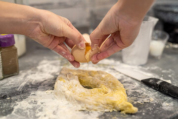 Beautiful young female hands break eggs into flour to knead a beautiful dough.