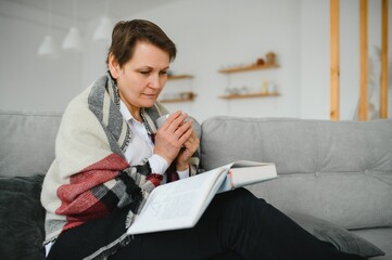 Senior woman reading book at home.