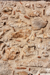 Old wall from large and small stones inside of cement mortar. Vertical photo.