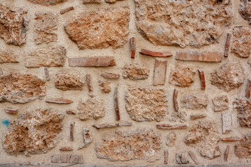 Antique masonry from blocks of different sizes in cement mortar. Horizontal photo.