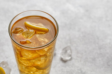 Iced cold summer drink. Glass of cold ice tea with lemon. Lemonade on grey background, close up. Copy space