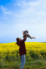 A woman holding her baby in a field on a beautiful sunny day