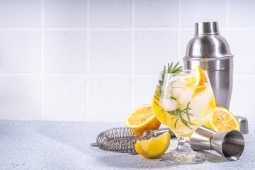Infused rosemary lemon drink. Cold detox citrus lemonade with carbonated fizz water, lemon slices and rosemary sprig, white tiled background copy space - obrazy, fototapety, plakaty