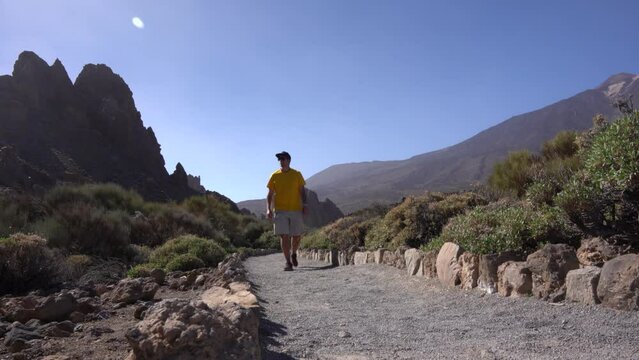 A tourist walking on the path between Roques de Gracia and Roque Cinchado in the natural area of Teide in Tenerife, Canary Islands