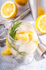 Infused rosemary lemon drink. Cold detox citrus lemonade with carbonated fizz water, lemon slices and rosemary sprig, white tiled background copy space