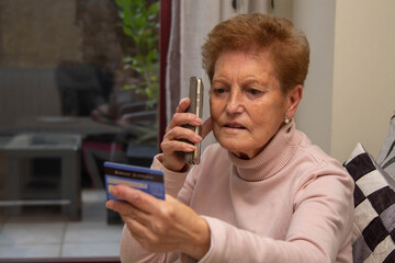 senior woman with credit card and phone doing online shopping from home