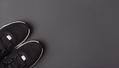 Black sneakers on a dark grey background. Top view, flat lay, space for text. 