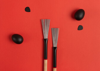 Drum brushes, shakers and guitar picks on a bright red background. Top view, flat lay.  