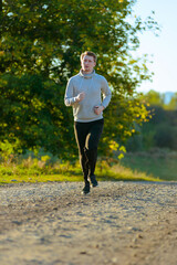 Running man jogging in rural nature at beautiful summer day. Sport fitness model caucasian ethnicity training outdoor.