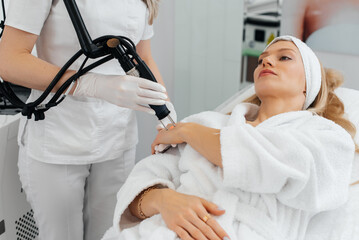 A young girl gets carbon peeling for the skin of her hands in a beauty salon. Laser pulses cleanse the skin. Hardware cosmetology. The process of photothermolysis, warming the skin.