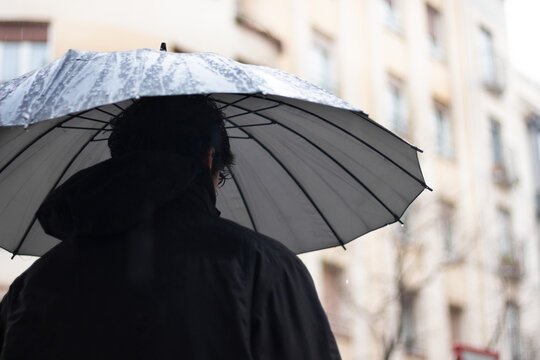 Back Person With Black Umbrella In The Rain And Building Background