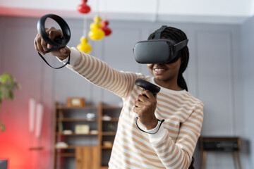 Excite black woman testing virtual reality device in digital world. College student girl hold controllers play shooter vr video game futuristic immersive simulator virtual reality 3D 360 cyber game