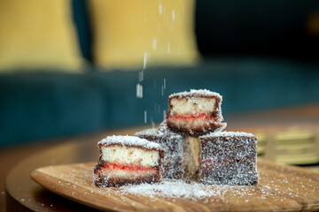 Lamington square cake Australian with coconut on a wooden board with sprinkles with grain and out...