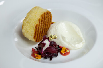 white plate with styled sweet sponge cake fig and ice cream gold leaves and flowers out of focus with grain