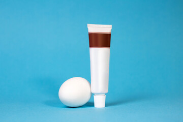 an egg and a tube of toothpaste without a logo on a blue background