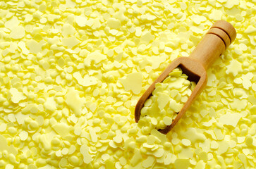 Pile of yellow sulfur granules used in medicine, fertilizers. Wooden spoon on yellow sulfur, top...