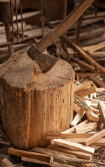 Old rusty ax with wooden handle stuck in the stump. blurred background with pile of wood logs, Large ax sticks out in felled wood of background of forest. Blurred background Concept: tool, work