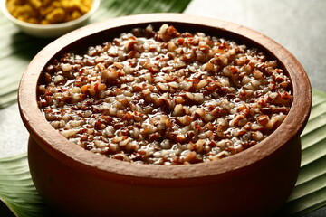 Homemade delicious red rice porridge, congee cooked in earthenware served with pickle and curry.