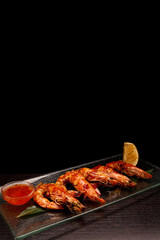 Grilled shrimp with sauce, on a black background