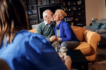 Female nurse talking to senior couple at nursing home.