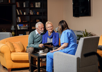 Female nurse talking to senior couple at nursing home.