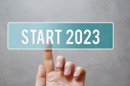 Finger pressing blue transparent start 2023 button on virtual interface on gray background with copy space for text. Concept of new year.
