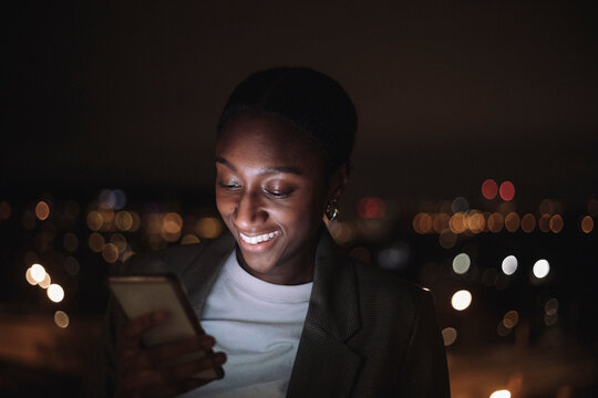 Happy businesswoman text messaging on smart phone at night