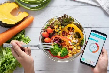 Foto op Plexiglas Calories counting , diet , food control and weight loss concept. Calorie counter application on smartphone screen at dining table with salad, fruit juice, bread and fresh vegetable. healthy eating © asiandelight