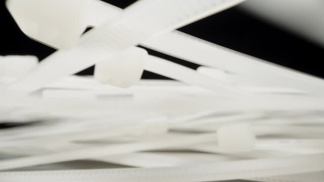 White nylon ties fall onto the table. Dolly slider extreme close-up. Laowa Probe