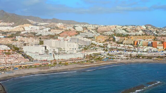 Aerial drone shot of Costa Adeje and Fanabe area, South Tenerife, Spain. Beautiful golden hour landscape. Premuim beaches and luxury hotels area. Drone flying backward